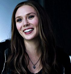 a woman with long brown hair smiling at the camera