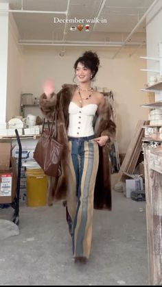 a woman is walking through a room with fur coats on her shoulders and handbag in her other hand