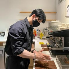 a man wearing a face mask standing in front of a counter with food on it