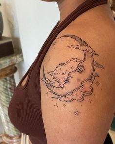 a woman with a tattoo on her shoulder is looking at the moon and stars in the sky