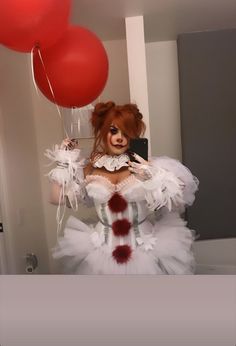 a woman dressed as a clown taking a selfie with red balloons in the background