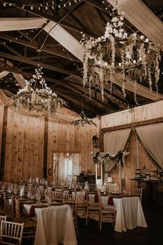 the inside of a barn with tables and chairs set up for a formal function or wedding