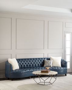 a living room with white walls and blue couches in front of a coffee table