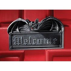 a metal sign that says welcome with a bat hanging from it's front door