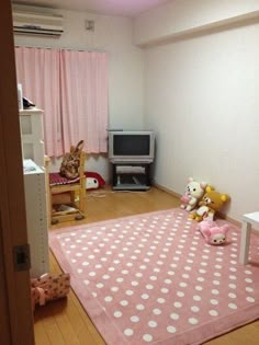 a pink and white polka dot rug in the corner of a room with a television