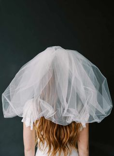 a woman wearing a white veil over her head and hair in the back, looking down