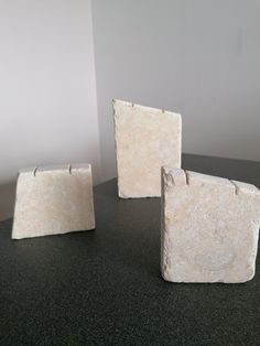 three pieces of white marble sitting on top of a table