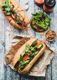 two sub sandwiches with lettuce, carrots and other toppings