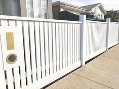 a white picket fence with a car parked in the back ground and houses behind it