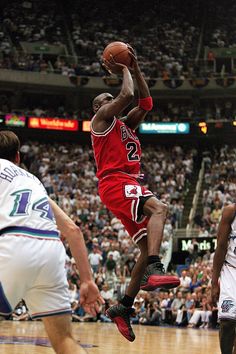 a basketball player jumping up to dunk the ball in front of two other players