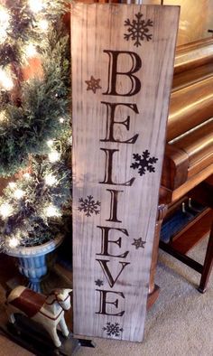 a wooden sign that says believe next to a christmas tree