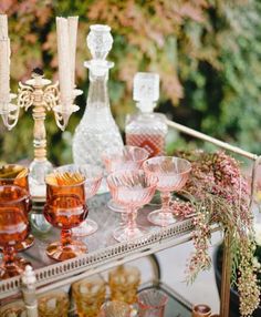 an assortment of wine glasses and candles on a table