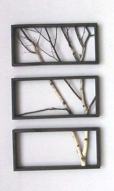 three metal frames with trees in them against a white wall