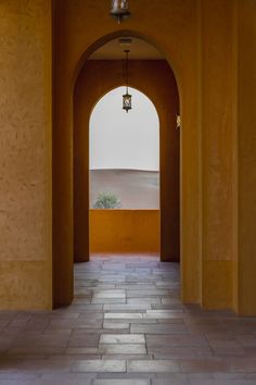 an archway leading into the desert with a light hanging from it's ceiling and tiled floor