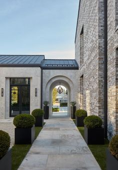 an entrance to a house with stone walls and black planters on either side of the walkway