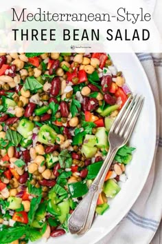 a white plate topped with beans and veggies next to a knife and fork