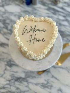 a heart shaped cake with the words welcome home written in it on a marble table