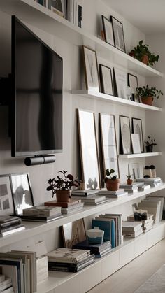 a living room filled with lots of books and pictures on the wall next to a flat screen tv