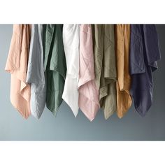 several different colored shirts hanging from hooks