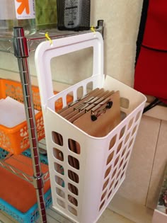 a white basket holding files and scissors on a shelf in a room with other office supplies