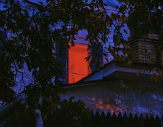 the red window is shining brightly in the dark night sky, and it appears to be partially obscured by leaves