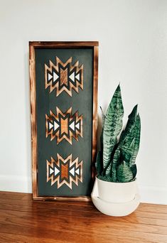 a potted plant sitting next to a wooden frame with geometric designs on it's sides