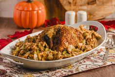 a turkey and stuffing dish on a placemat with pumpkins in the back ground