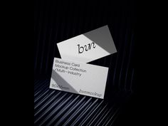 two business cards sitting next to each other on top of a black surface with the word bon printed on it