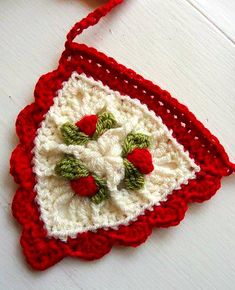 a crocheted ornament with red and white flowers on the front, attached to a string