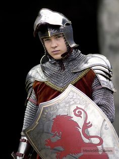 a young man dressed in armor and holding a shield with a lion on it's side