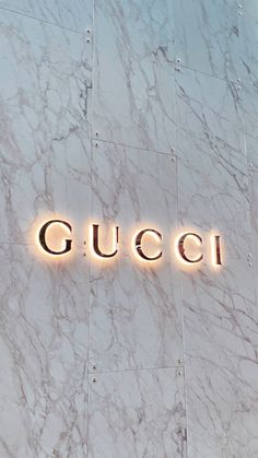 the gucci sign is lit up in front of a building with marble walls and flooring