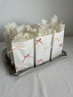 three bags with white paper on them are sitting on a silver tray and one bag has red scissors in it