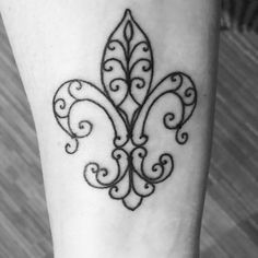 a black and white photo of a tattoo design on the leg, with an ornate fleur de lis