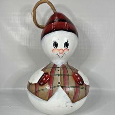 a ceramic snowman ornament with a red hat and scarf on it's head