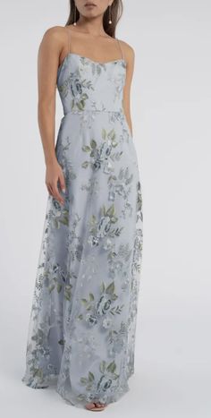 a woman is wearing a long dress with flowers on the side and spaghetti straps,