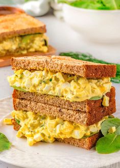 two sandwiches stacked on top of each other with lettuce and eggs in between them