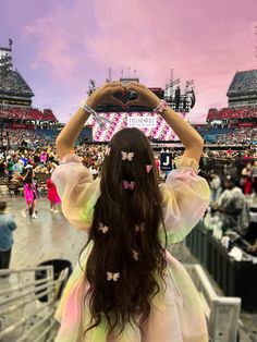 a woman with long hair holding up a cell phone in front of her head at a concert