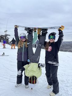 two girls holding up their snowboards on top of a ski slope