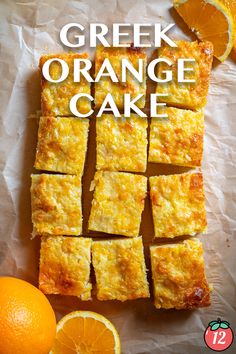 an orange cake cut into squares on top of a piece of wax paper next to sliced oranges