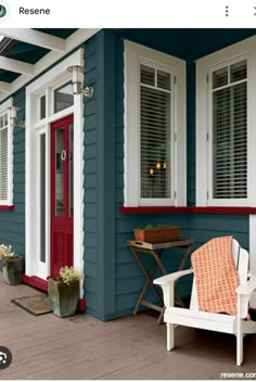 a blue house with white shutters and red door on the front porch is shown