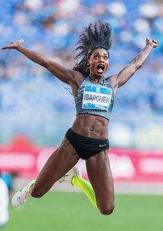 a female athlete jumping in the air with her arms wide open and legs spread out