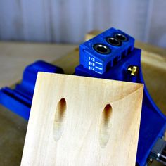 a wooden object with two holes in the middle, and a blue machine behind it