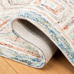 a close up of a rug on the floor with a wooden floor in the background