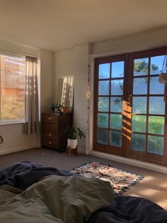 a bedroom with a bed, dresser and large window in the corner that overlooks a grassy field