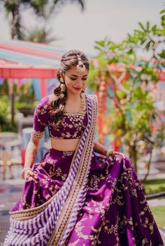 a woman in a purple and gold lehenga