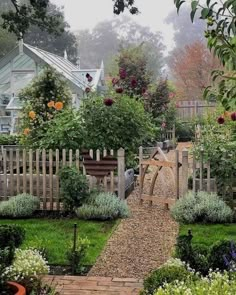 a garden with lots of plants and flowers on the side of it, surrounded by wooden fences