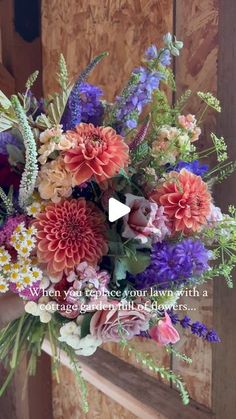 a vase filled with lots of colorful flowers on top of a wooden door frame in front of a building