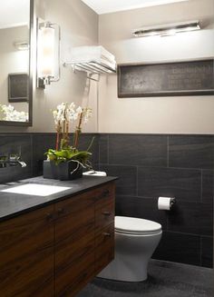 a white toilet sitting next to a sink in a bathroom under a mirror and lights