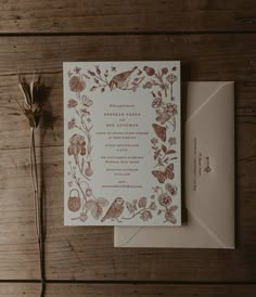 the wedding stationery is laid out on top of the wooden table next to an envelope