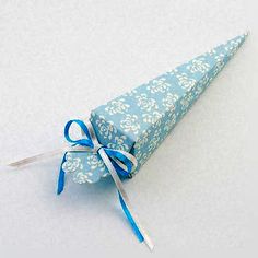 a blue paper cone with white flowers on it and a ribbon tied around the top